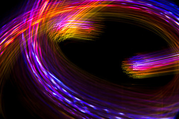 Abstract blurred space comet, multi-colored light lines on a black background.