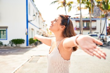Young beautiful woman at the colorful village of Puerto de Mogan, smiling happy sunbathing with...