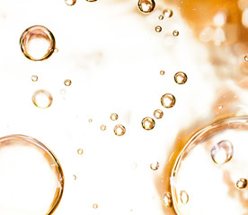 Bubbles of air on the smooth surface of golden water as an abstract background