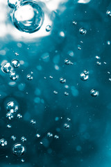 Bubbles of air on the smooth surface of blue water as an abstract background