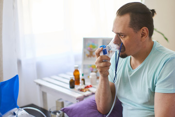 a sick man breathes through an inhaler mask - obrazy, fototapety, plakaty