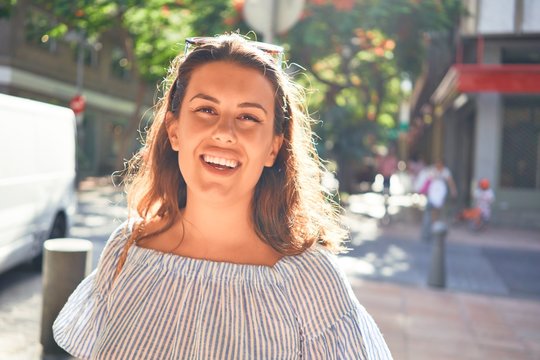 Young beautiful woman smiling happy walking on city streets on a sunny day of summer