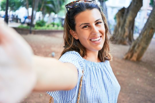 Young beatiful woman smiling happy and cheerful at green park taking a selfie using smartphone on a sunny day of summer