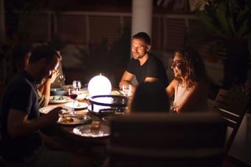 Beautiful family on dinner talking and smiling at terrace
