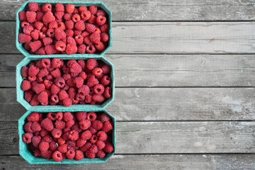 Fresh red raspberries in craft stalls, containers. on a wooden rustic old background. Top view of ripe berries. Autumn harvest.