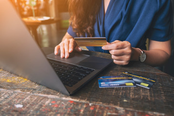 Closeup image of a business woman holding credit cards while using laptop computer