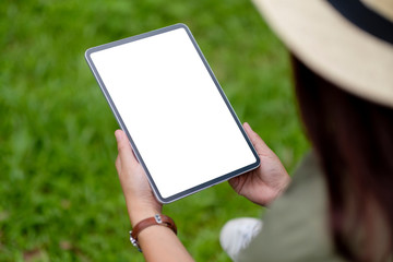 Fototapeta na wymiar Mockup image of a woman holding black tablet pc with blank white desktop screen in the park
