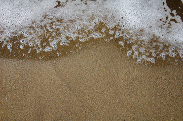 sea water and foam on the sandy shore. Space for text