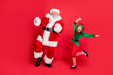 Full body photo of excited two santa claus in hat headwear dancing on festive event wearing green...