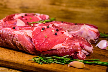 Raw ribeye steak, spices, rosemary and garlic on cutting board