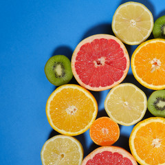 Fototapeta na wymiar Fresh summer fruits on blue background. Healthy food concept. Flat lay. Tropical summer mix grapefruit, orange, mandarin, kiwi, lemon