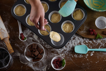 The process of making cupcakes, coating a cream from a pastry bag in the hands of a pastry chef.