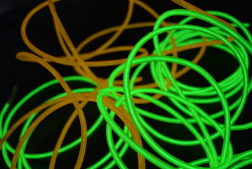 Bright luminous yellow and green, lime neon wires in different formats and layouts. An electroluminescent wire, a neon light guide, an ice tube are folded into different structures and shapes.