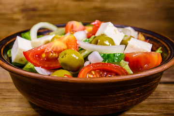 Ceramic plate with greek salad on wooden table