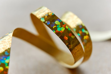 Golden curly ribbon on brown kraft paper background. Serpentine with curls for use as a christmas, anniversary, marriage, wedding or celebration background. 