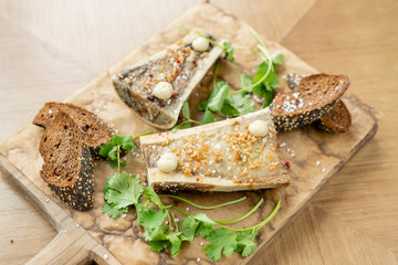 Beef bone marrow with chimichurri sauce and toasted bun. Served on a chopping wooden Board. Menu BBQ restaurant