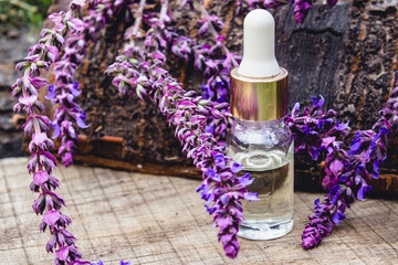 Obraz na płótnie Canvas Lavender essential oil in a glass bottle and lavender colors on a rustic wooden background. Tincture or essential oil with lavender. herbal medicine.