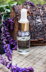 Obraz na płótnie Canvas Lavender essential oil in a glass bottle on a wooden table near the branches of blooming lavender. Tincture or essential oil with lavender. herbal medicine.