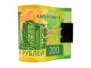 A folded bundle of Russian banknotes in two hundred rubles stands on a white background. Banknotes are fastened with a clerical clip. Not isolated. Macro