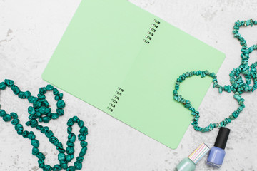 girlish flat lay with empty notebook or diary with green pages and beads and nail polish bottle with space for text.