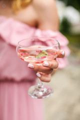 Close up female hand holding cocktail on party. unrecognizable girl in a pink dress holds a glass with champagne