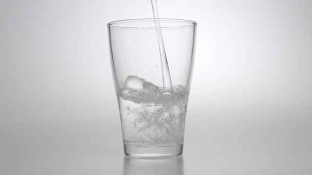 Slowmotion fresh mineral water pouring in to a glass .healty food and drink concept.cold beverage refreshing .
