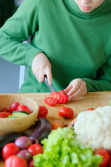 Obraz na płótnie Canvas girl slices tomatoes to make a salad. 