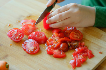 girl slices tomatoes to make a salad.