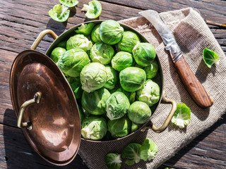 Brussel sprouts in the copper pan on the old wooden table.
