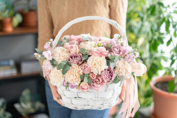 Flower arrangement in Wicker basket. Beautiful bouquet of mixed flowers in woman hand. Floral shop...