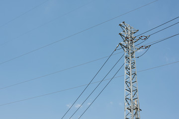 City steel high voltage tower and power lines closeup on sky background
