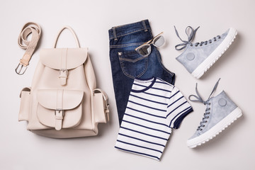 Clothing outfit - white backpack, jeans, striped t shirt, blue sneakers - obrazy, fototapety, plakaty