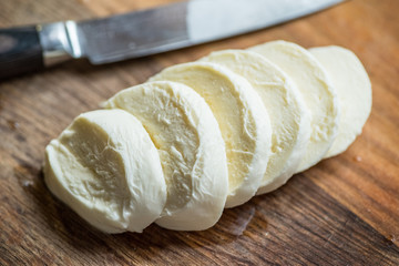 Slices of water buffalo cheese mozzarella on wood background.
