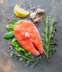 Raw salmon with spices and vegetables on the graphite board.