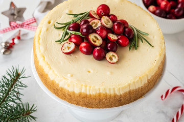 Cheescake with fresh cranberry and rosemary. Christmas cake with decoration on white background.