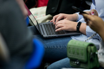 A picture of laptop. Girl holds it on her lap. She has her fingers on its keyboard. Woman types. She works