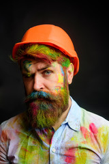 Serious painter worker man in hard hat. Professional house painter. Male painter in paint splattered shirt. Room painting job. Designer man in working clothes. Handsome decorator, builder, repairman.