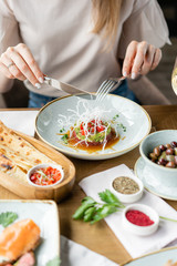 Closeup woman eating tartar in the restaurant. Variety of dishes on the table. Italian cuisine