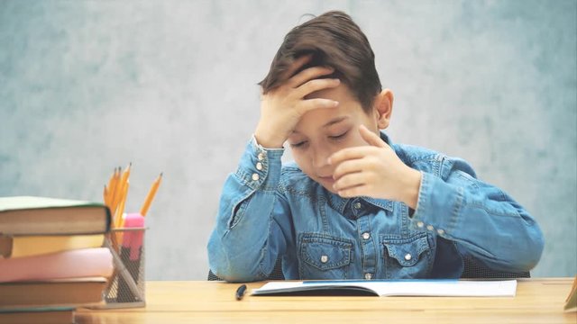 Young clever school kid in blue jeans t-shirt was writing and made a mistake. Now he doesn't know how to correct it.
