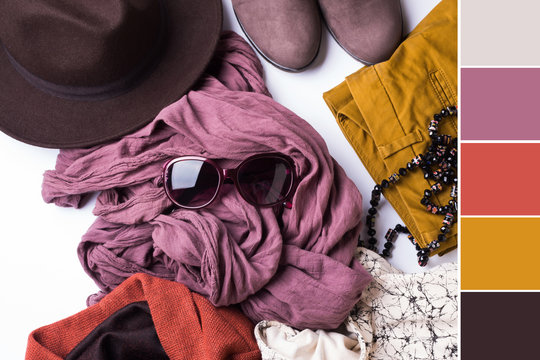 Flat lay with lady's clothes, hat, sun glasses, necklace. Autumn colours accessories on white background. Color swatch