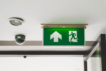 fire exit sign on ceiling with opened door for emergency case
