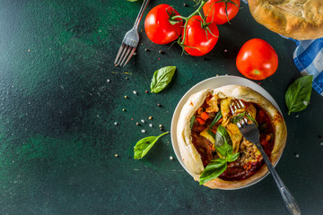 Two portion homemade Chicago Pizza Pot Pie with cheese, minced beef meat and vegetables, with pots and ingredients on domestic table copy space