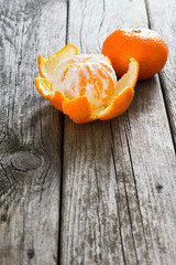 peeled and whole tangerines on old wood table