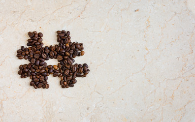 Hash tag icon symbol made from roasted coffee beans on marble surface flat lay image with copy space for text.