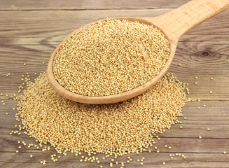 Amaranth seeds in wooden spoon on wood background.