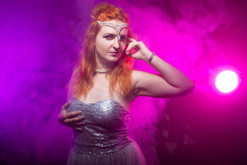Naklejka premium Mature plus size red hair woman in grey evening dress posing on dark smoke background ready for halloween.