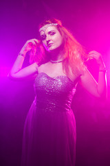 Mature plus size red hair woman in grey evening dress posing on dark smoke background ready for halloween.