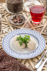 Fish meatball with parsley on white plate and glass of red drink on oriental wooden table