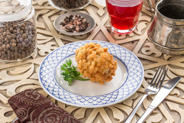 Kiev cutlets with bread croutons on white plate and glass of red drink on oriental wooden table