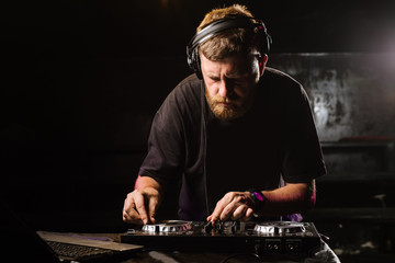 DJ plays on a mixer in the club on black background